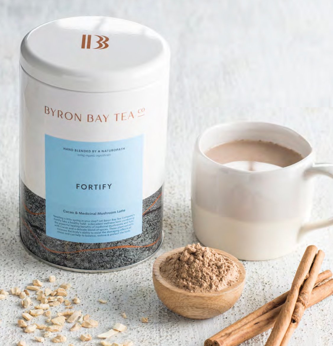 Byron Bay Tea Company fortify leaf tin with cup of fortify and bowl of tea leaf powder and cinnamon stick next to it
